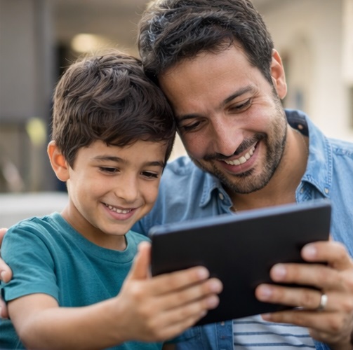A father and son looking at an ipad while doing telehealth speech therapy